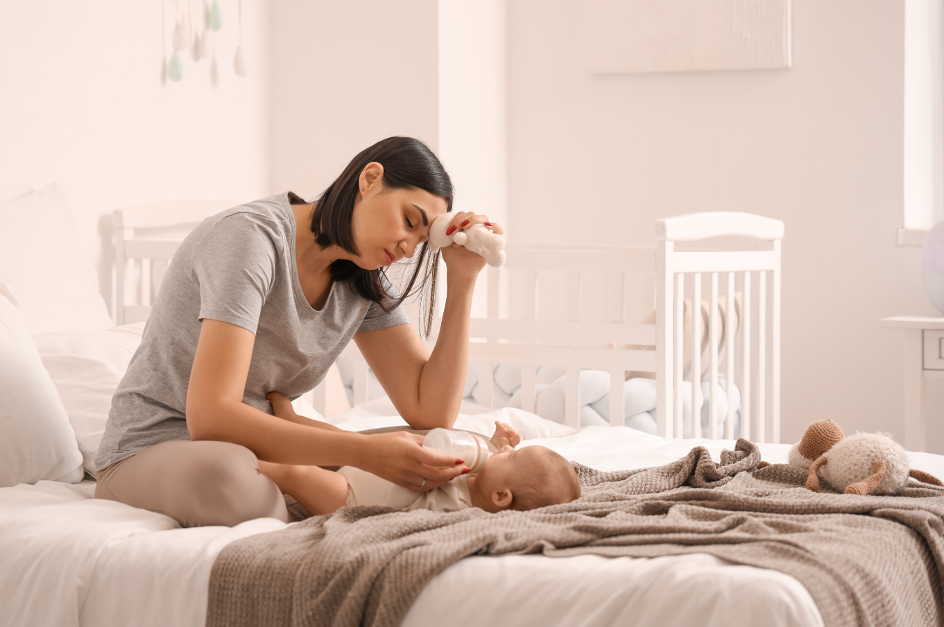 Depressed young woman feeding her baby in the bedroom
